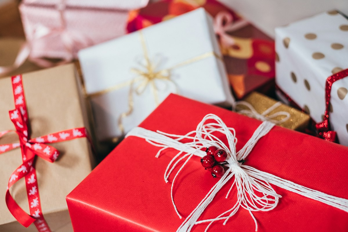 Mesa de madera llena de regalos originales envueltos en papel kraft, cintas y etiquetas hechas a mano, lista para una ocasión especial