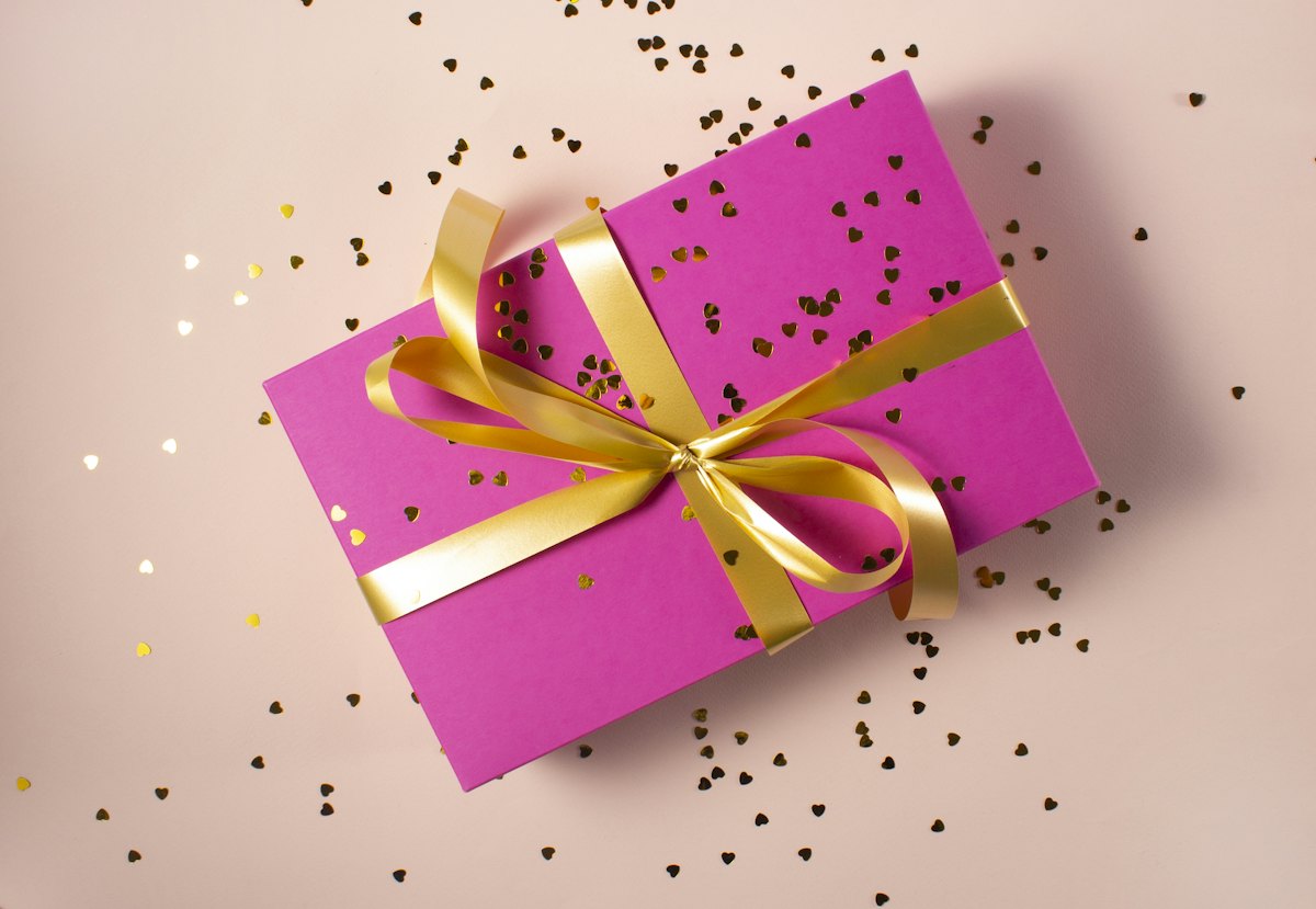 Varias cajas para regalos de cartón kraft y rígidas con lazos y papel de seda sobre una mesa de madera